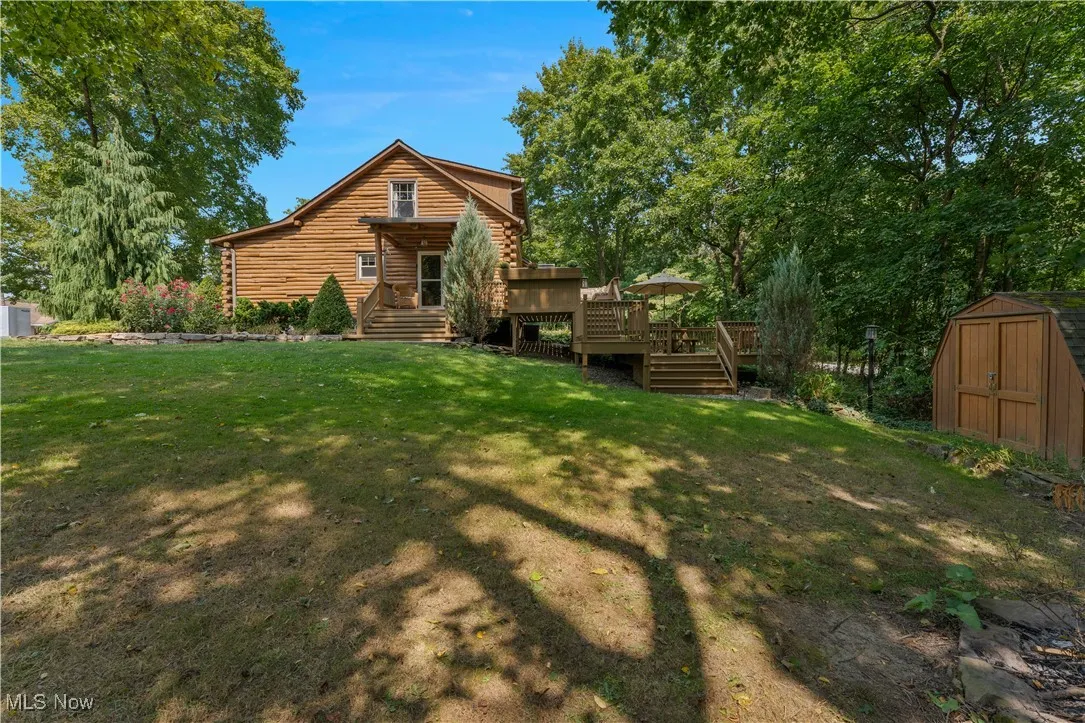 Rear view of property with log exterior, a yard, and a deck