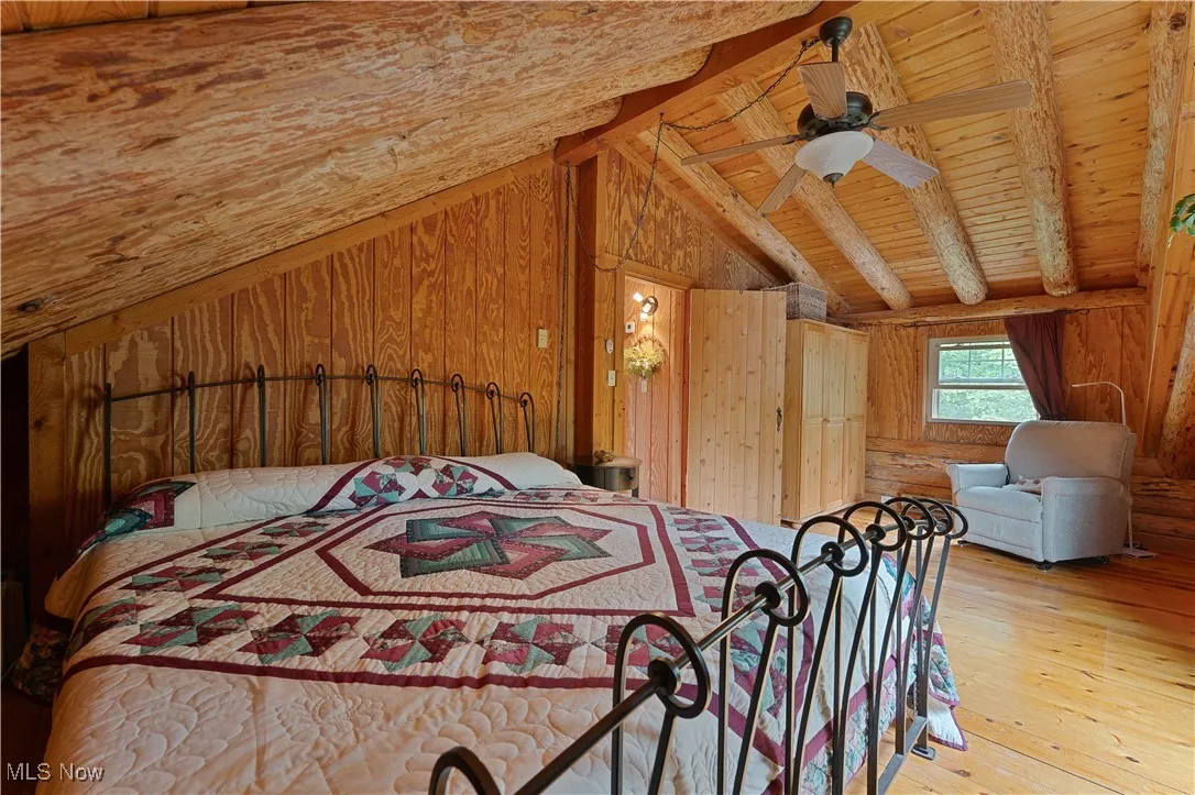 Bedroom with wooden walls, light wood-style flooring, a ceiling fan, and wood ceiling