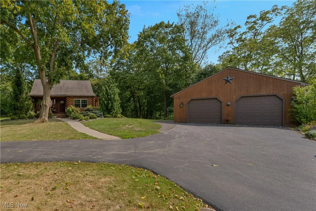 View of front of property with a detached garage, covered porch, an outbuilding, and a front yard
