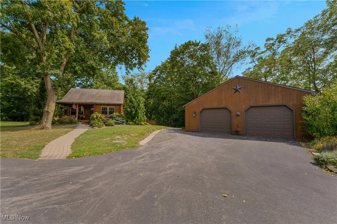 View of front of home with an outbuilding, covered porch, a front lawn, and a garage