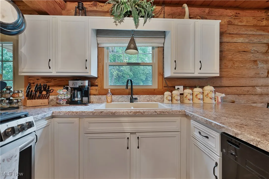Kitchen featuring white cabinetry, stainless steel range with gas stovetop, and black dishwasher
