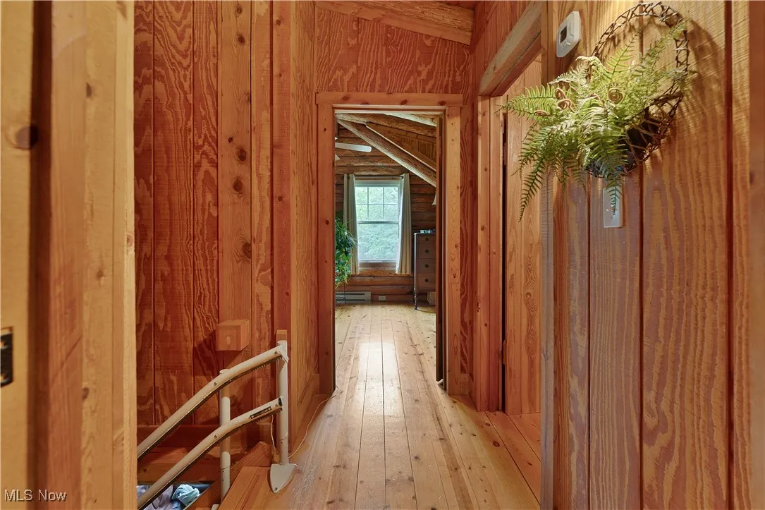 Hall with wood walls and hardwood / wood-style floors