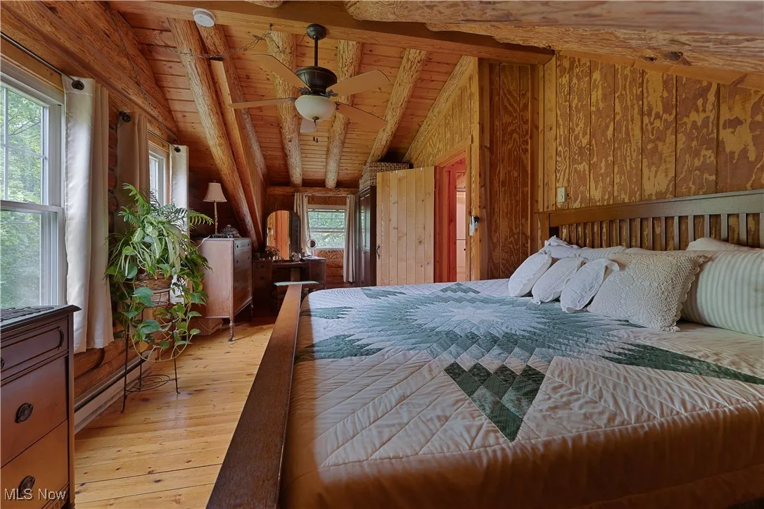 Bedroom with wood walls, light wood finished floors, wood ceiling, and ceiling fan