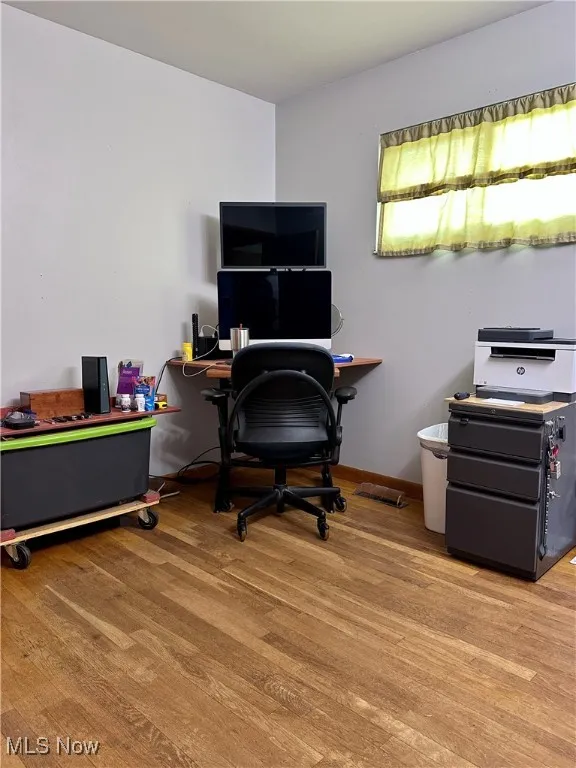 Home office/bedroom featuring light wood-type flooring and baseboards