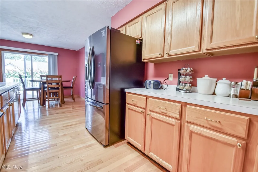 Kitchen featuring light brown cabinetry, stainless steel fridge with ice dispenser, a textured ceiling, and light countertops