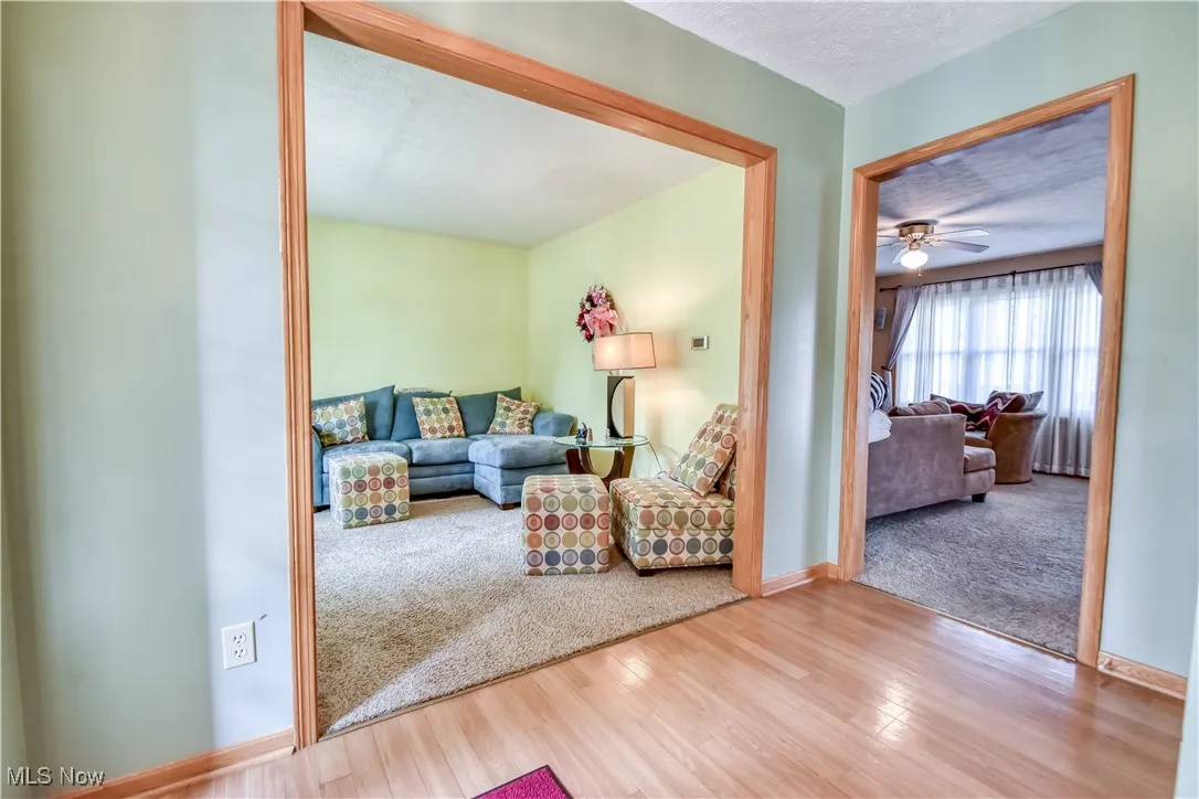 Living area with a textured ceiling, wood finished floors, carpet floors, and a ceiling fan