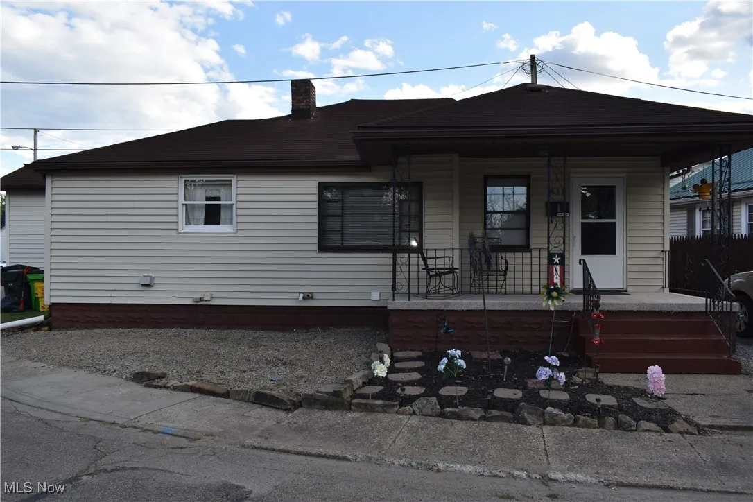 View of front facade featuring covered porch and a chimney