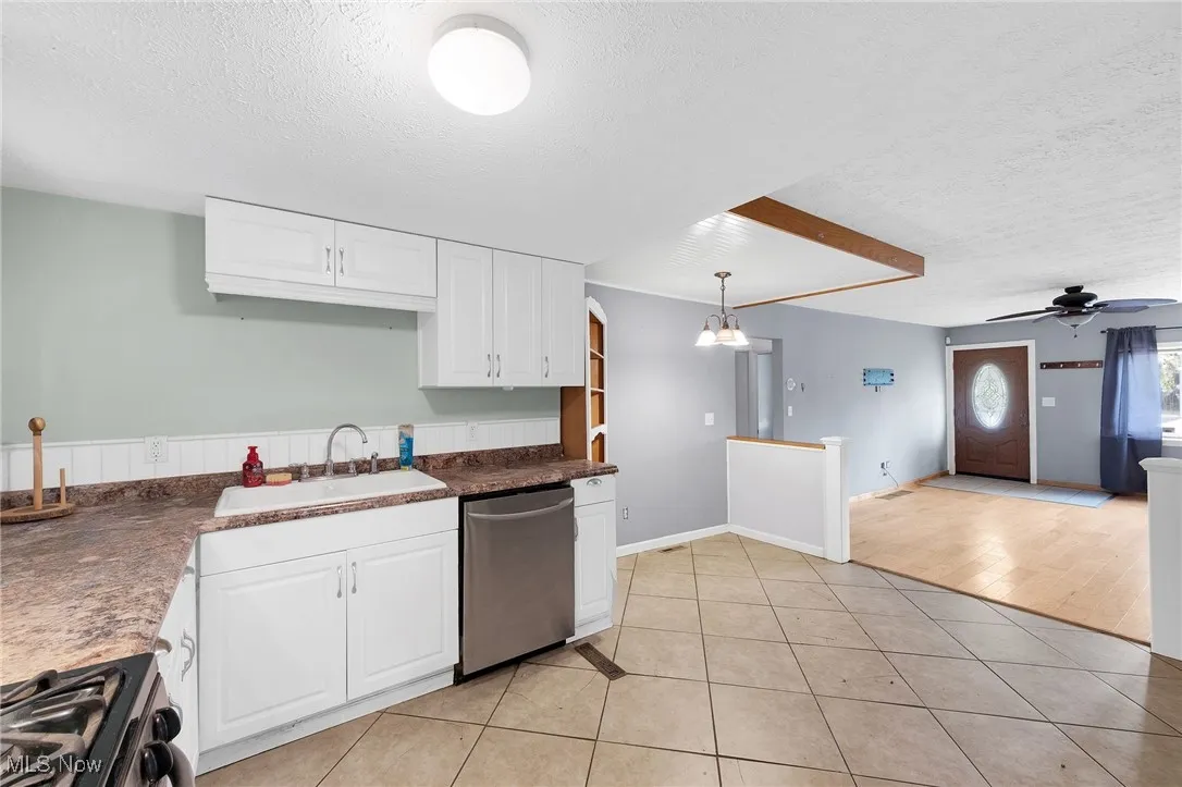 Kitchen featuring a textured ceiling, white cabinets, ceiling fan, dark countertops, and light tile patterned floors