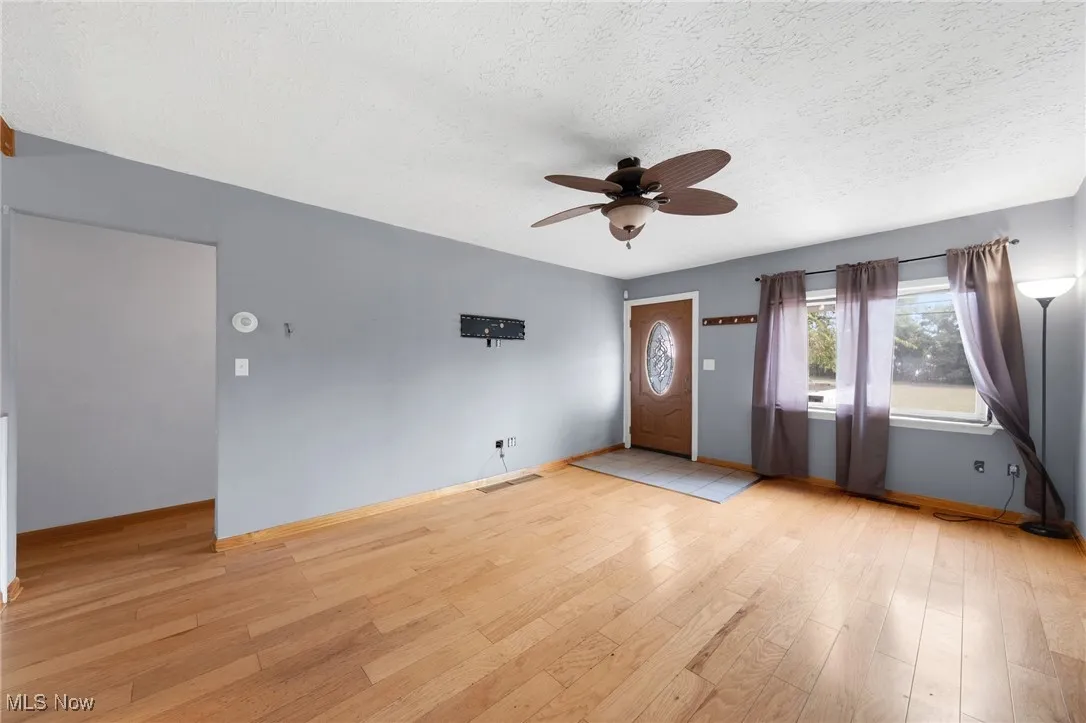 Entrance foyer with ceiling fan, light wood-style floors, and a textured ceiling