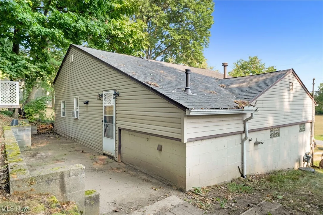 View of property exterior featuring a shingled roof and a garage
