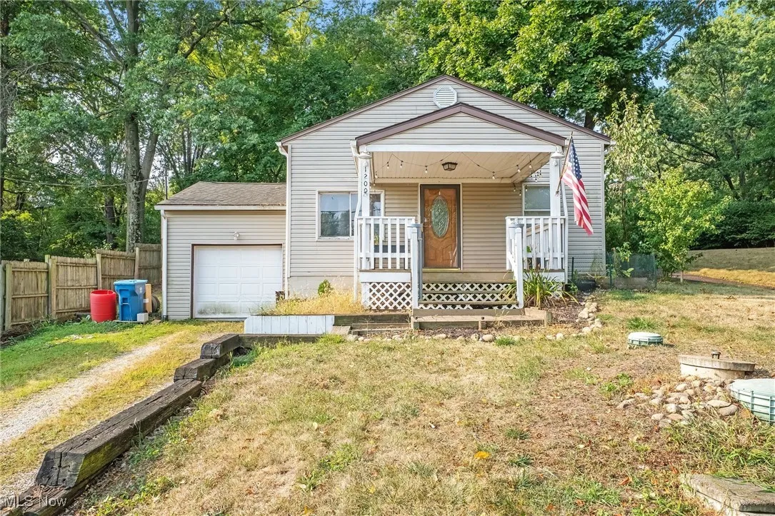Bungalow-style home with driveway, a porch, and view of scattered trees
