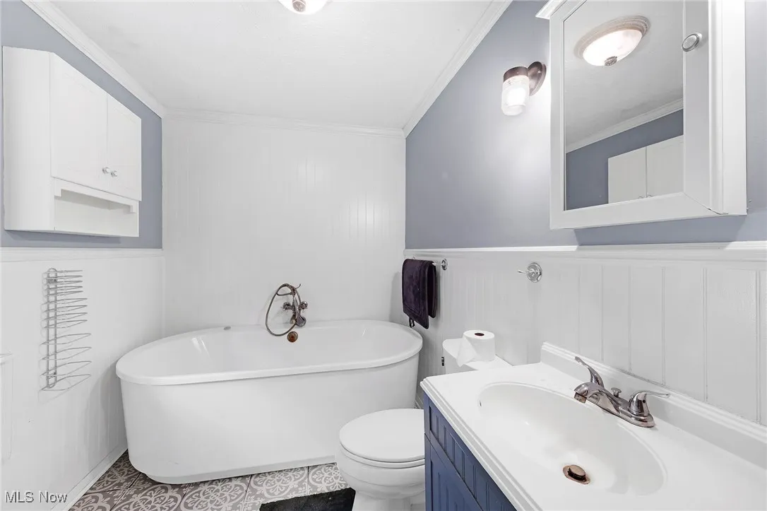 Bathroom with crown molding, a freestanding bath, and vanity