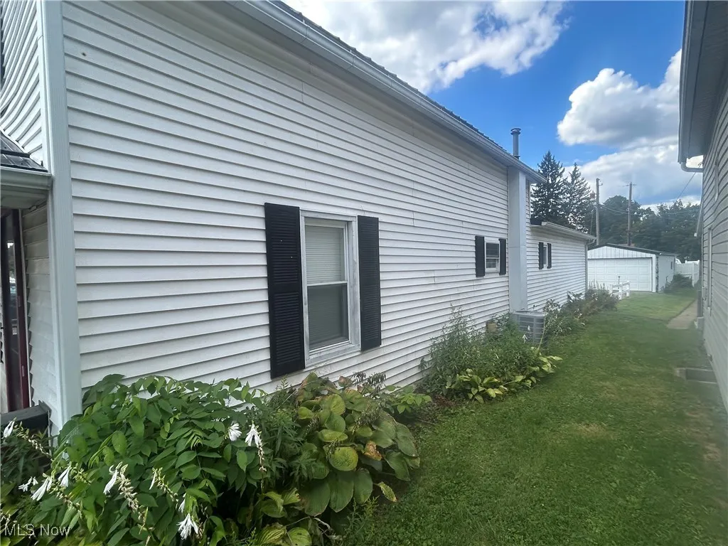 View of side of property with a yard and an outbuilding