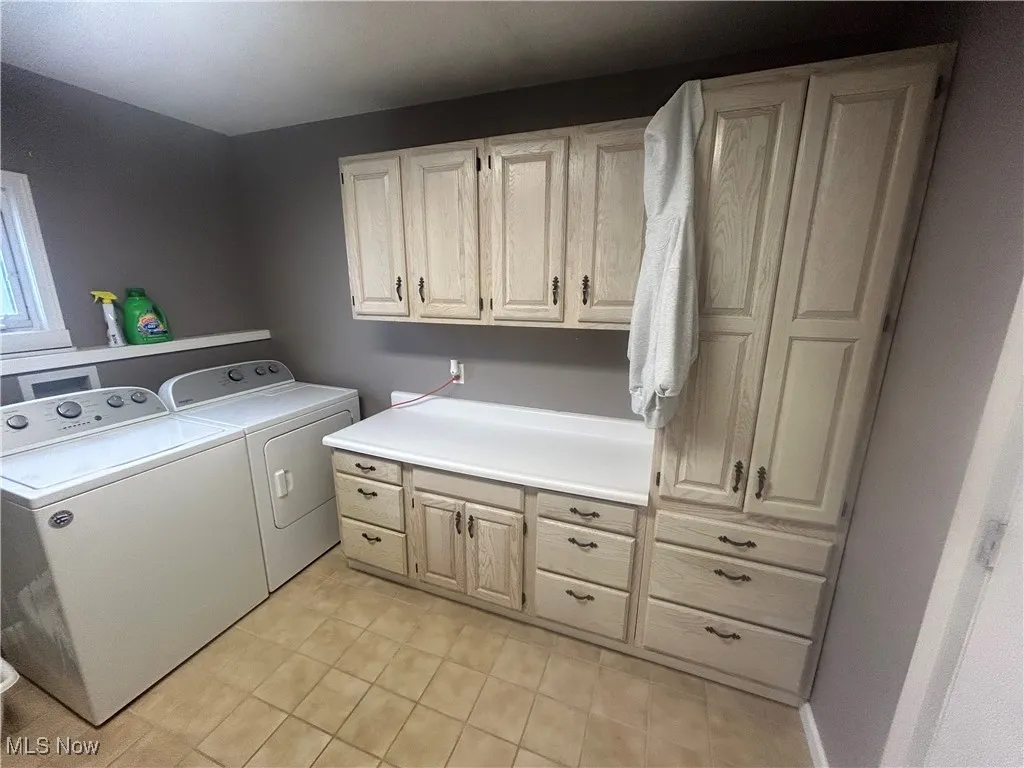 Laundry room with separate washer and dryer, cabinet space, and light tile patterned floors