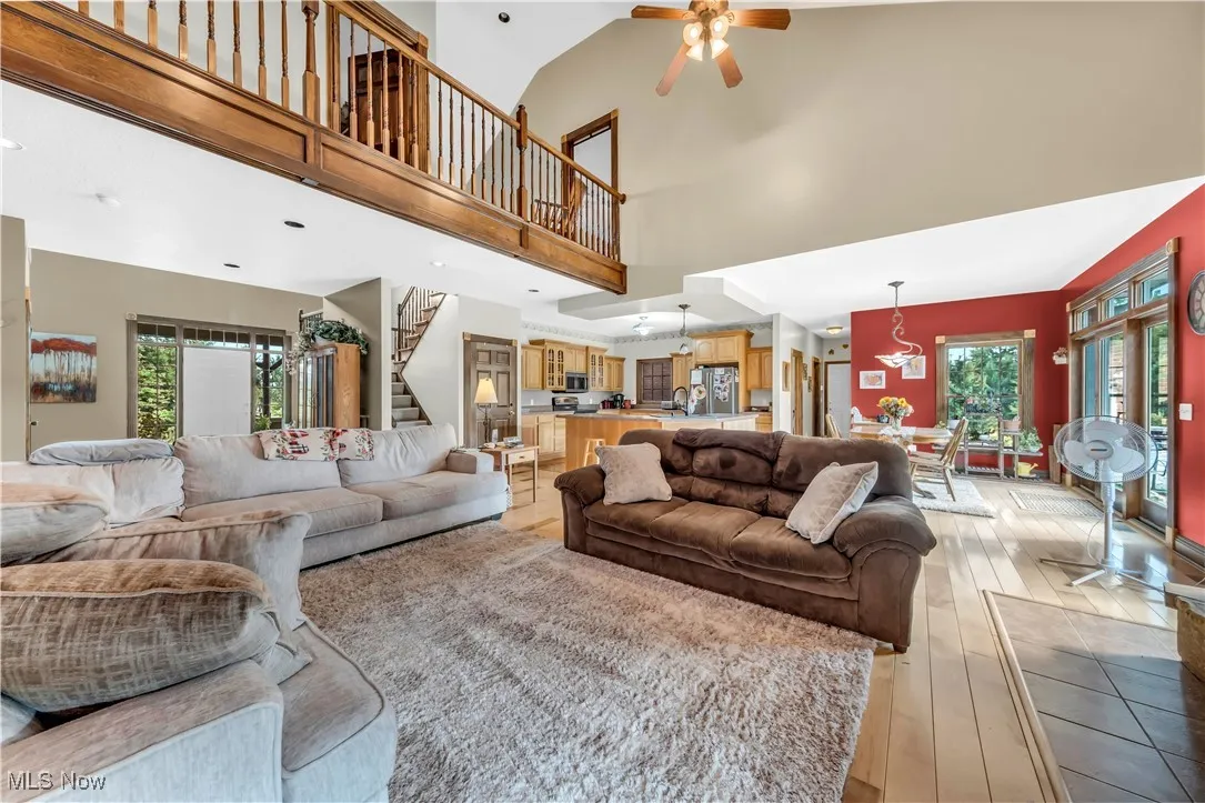 Living area featuring stairs, hardwood / wood-style floors, a ceiling fan, and a high ceiling