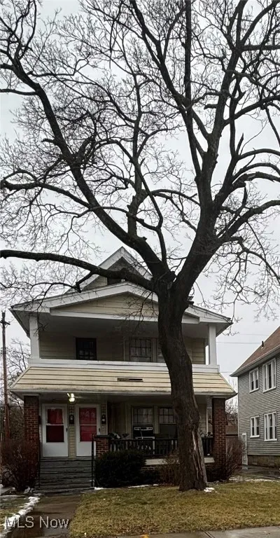 View of front of property featuring brick siding, a porch, and a front yard