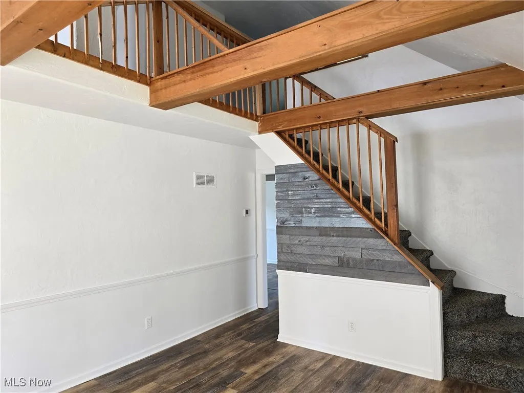 Staircase featuring wood finished floors and beamed ceiling