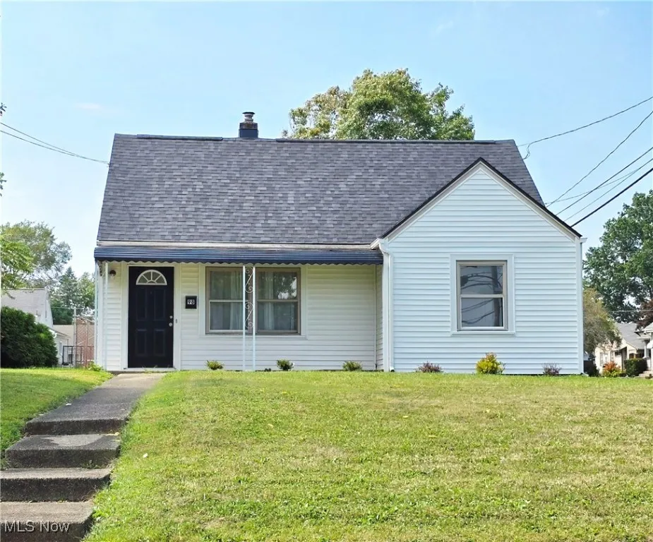 View of front of house with a shingled roof, a front yard, and a chimney