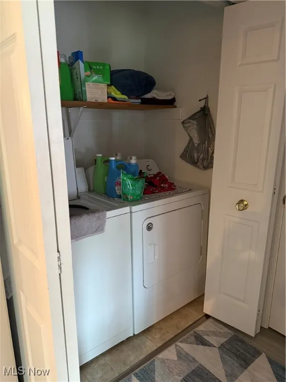 Washroom with washer and clothes dryer and light tile patterned flooring