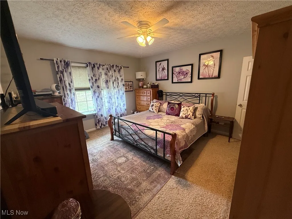 Bedroom featuring a textured ceiling, carpet floors, and a ceiling fan