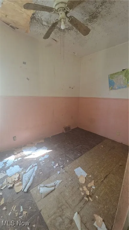 Empty room with ceiling fan and a textured ceiling