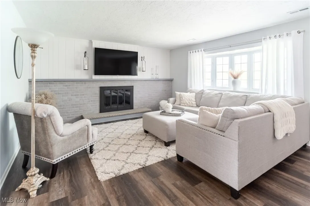 Living area featuring a textured ceiling, a fireplace, and dark wood-type flooring