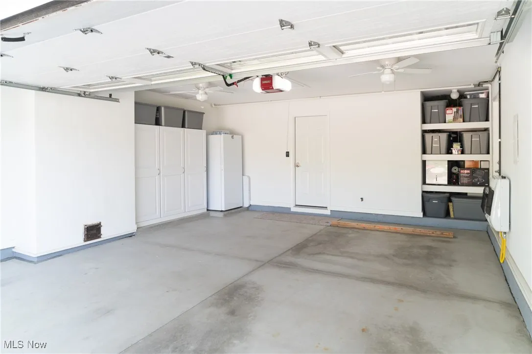 Garage with heating unit, ceiling fan, and a garage door opener