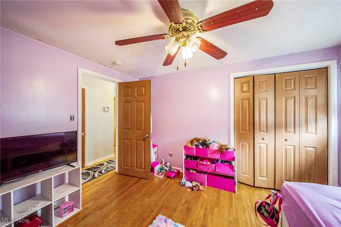 Bedroom featuring wood finished floors, a closet, and a ceiling fan