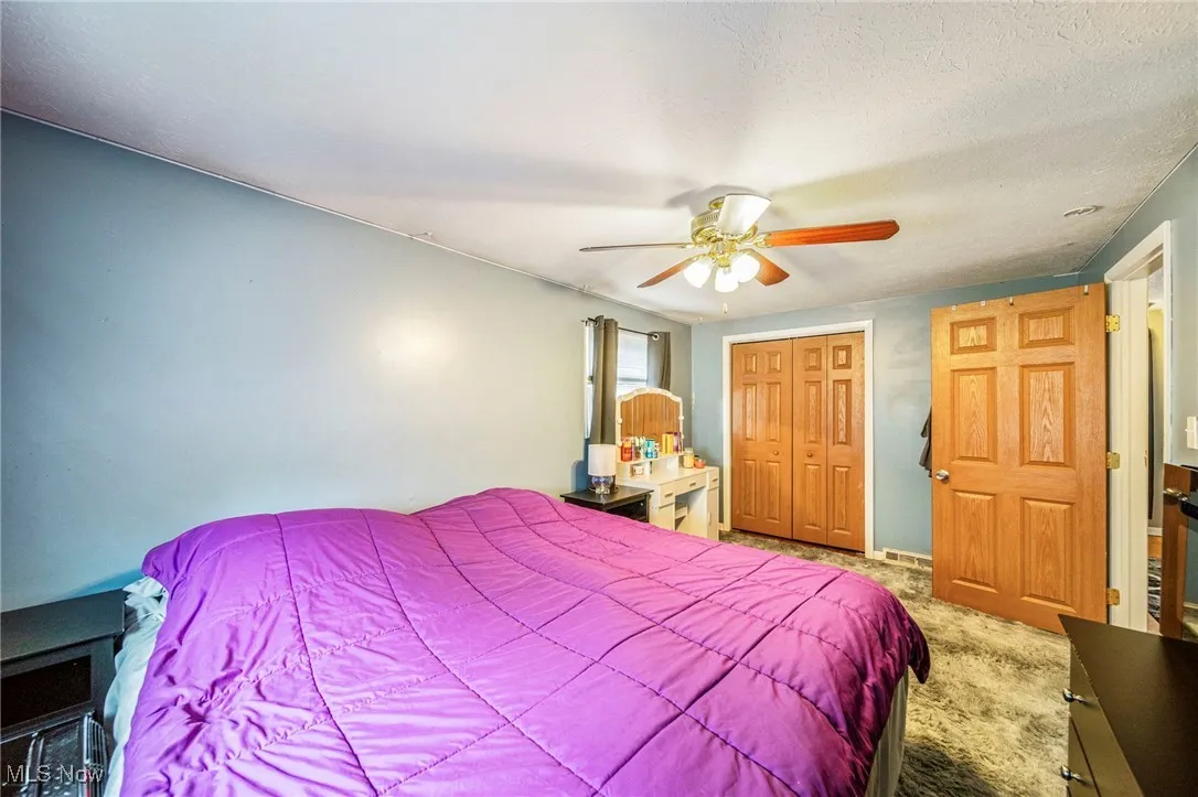 Bedroom with carpet floors, a closet, ceiling fan, and a textured ceiling