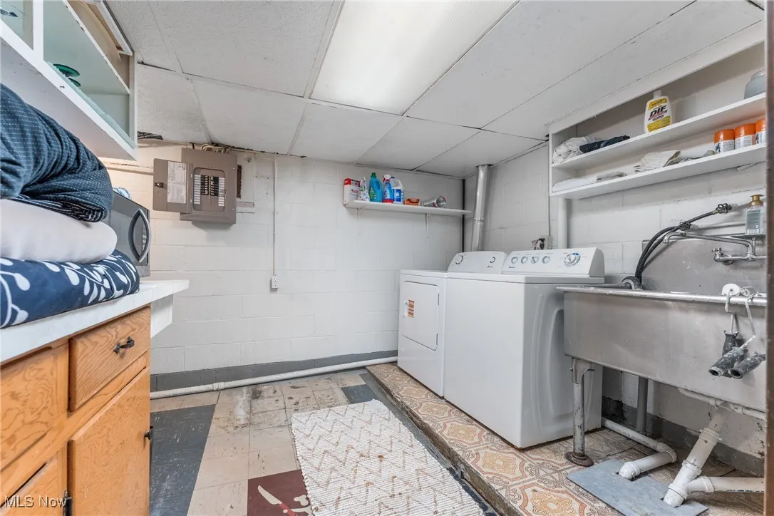 Laundry room with washing machine and clothes dryer, electric panel, and light flooring