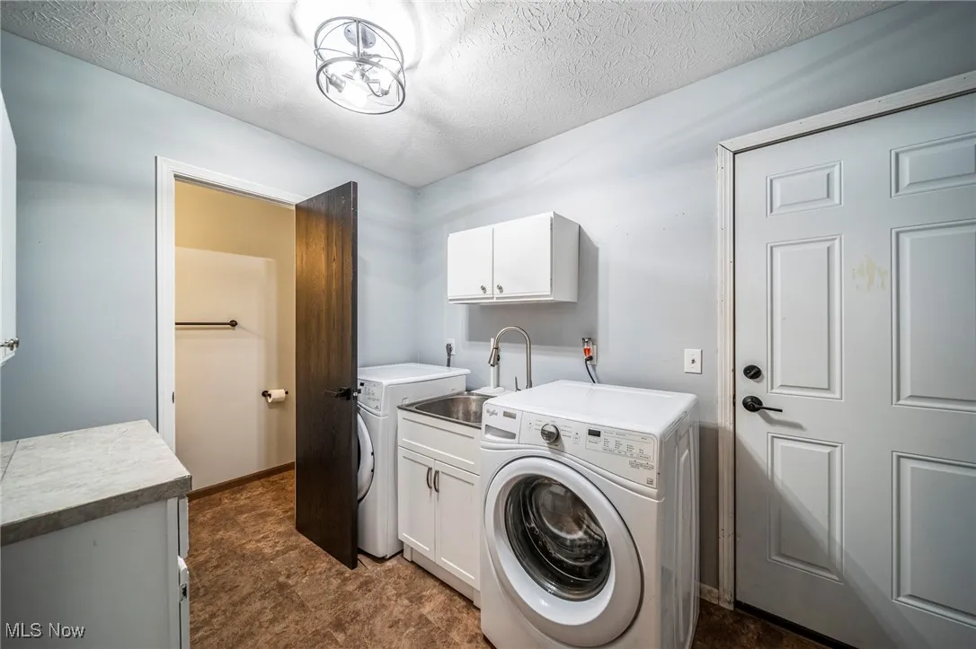 Laundry room featuring a textured ceiling, cabinet space, and independent washer and dryer