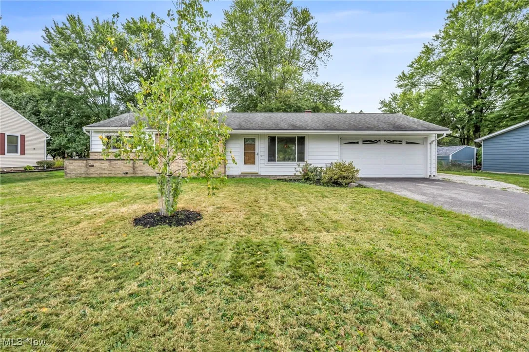 Ranch-style home featuring asphalt driveway, a front yard, and an attached garage