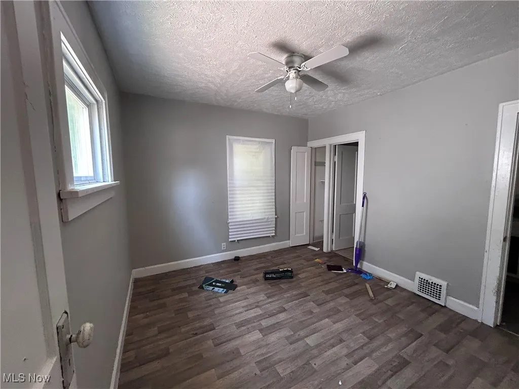 Exercise area with wood finished floors, a textured ceiling, and ceiling fan