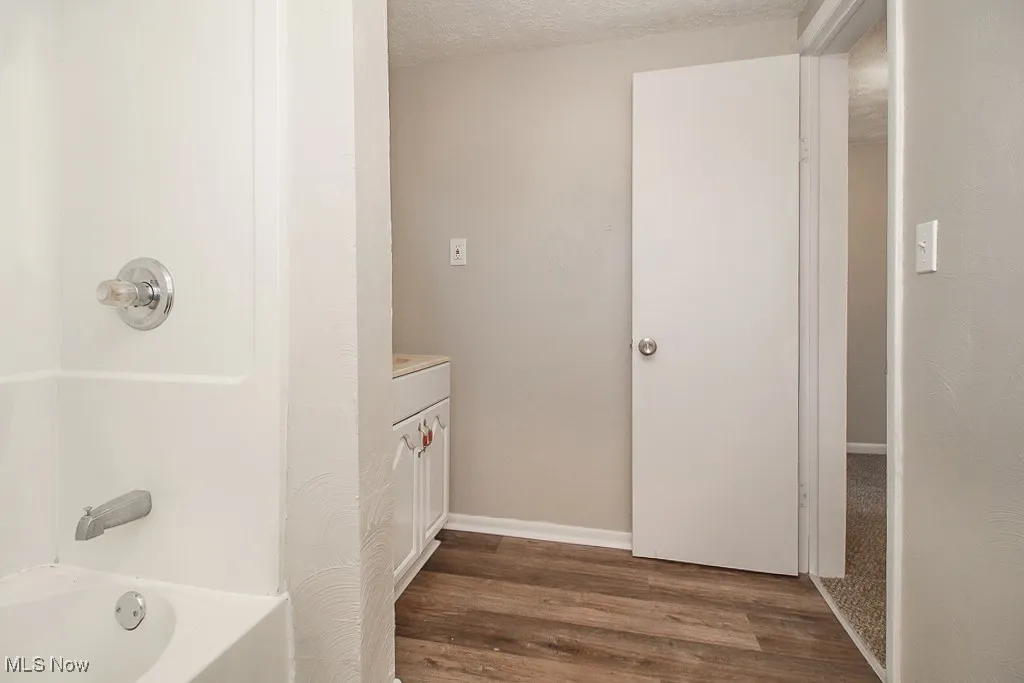 Bathroom with a textured ceiling, vanity, dark wood-style flooring, and shower / bathtub combination