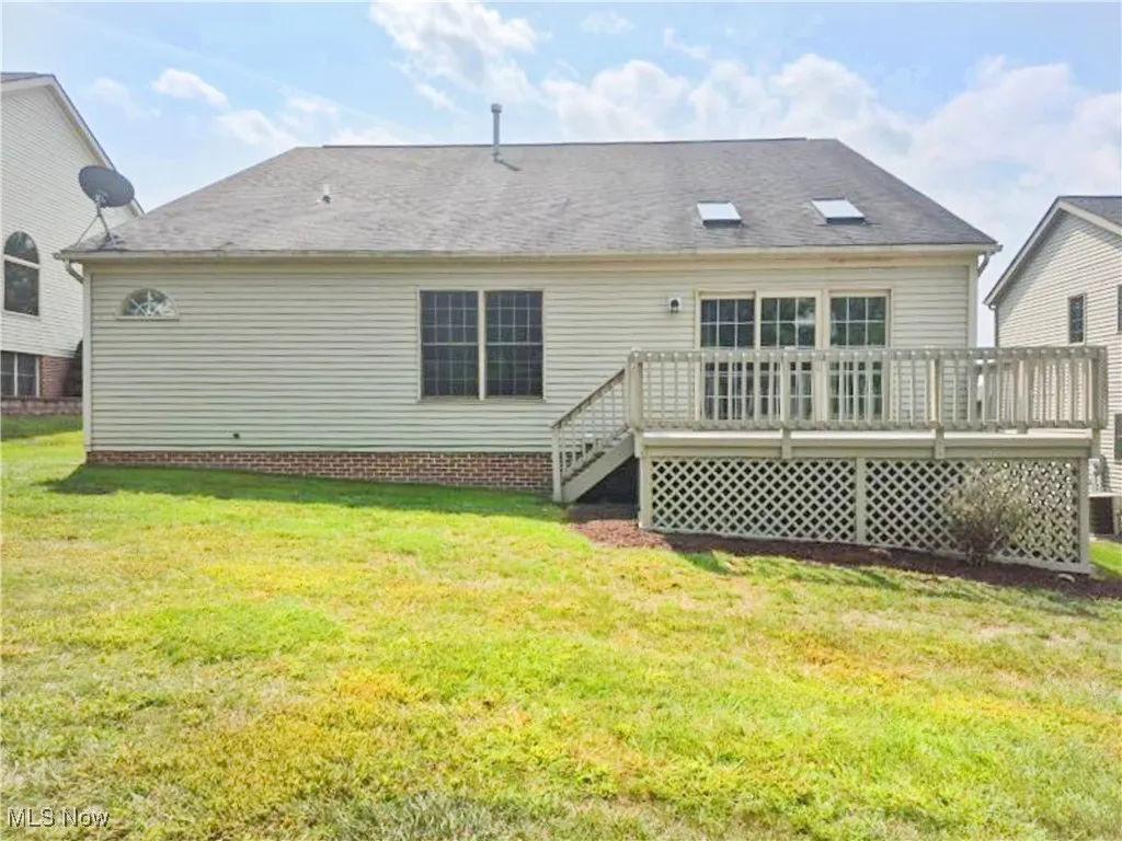 Back of property featuring a wooden deck and a yard