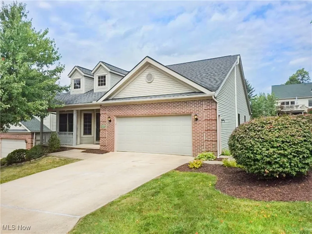 View of front of house featuring brick siding, covered porch, concrete driveway, a garage, and a shingled roof