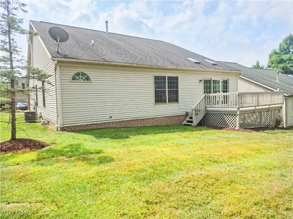 Rear view of property featuring a wooden deck, a yard, and roof with shingles