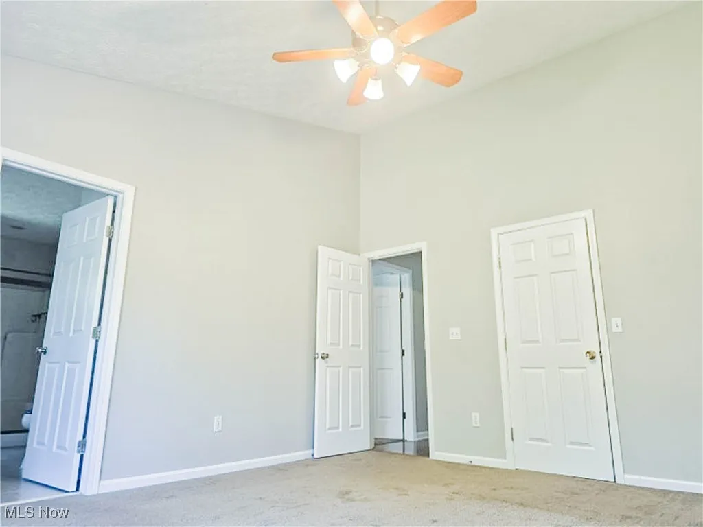 Unfurnished bedroom with carpet flooring, ceiling fan, connected bathroom, a towering ceiling, and a textured ceiling