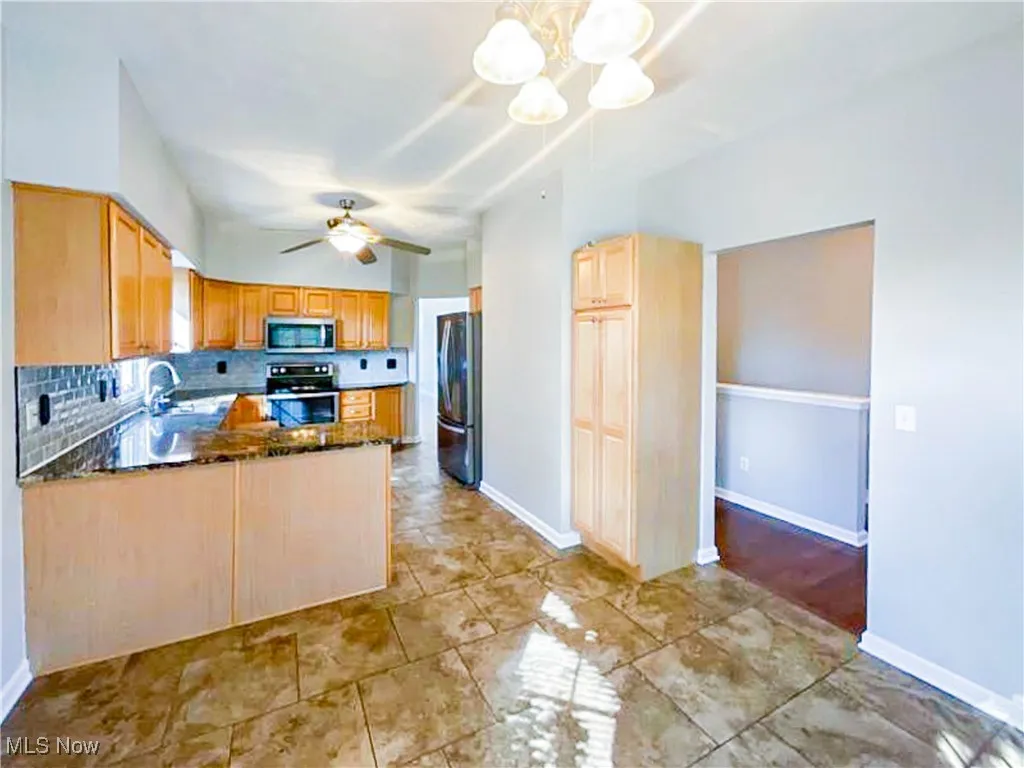 Kitchen featuring backsplash, a chandelier, granite countertops