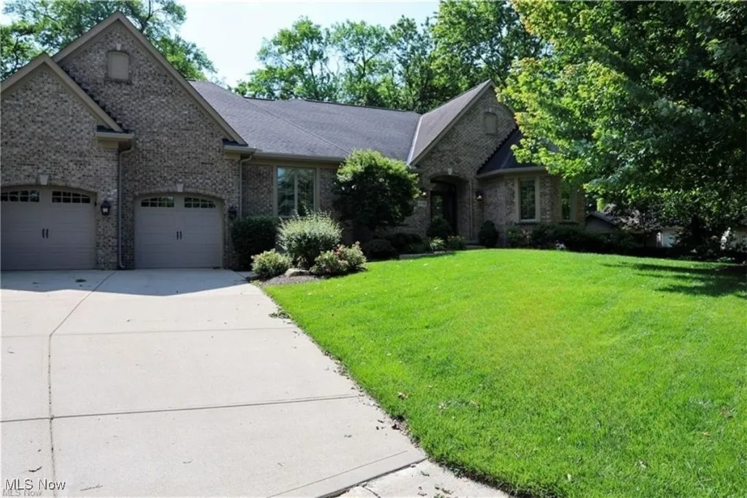 View of front of property featuring a front lawn, concrete driveway, and brick siding