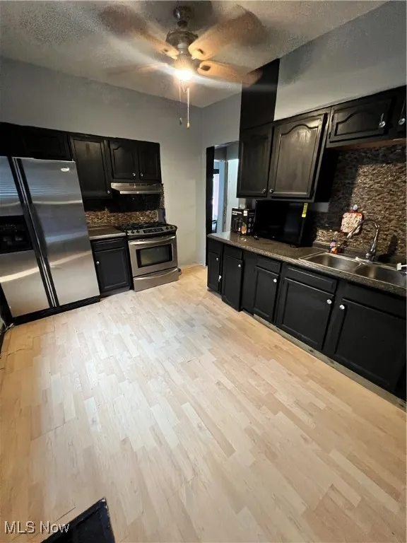 Kitchen featuring decorative backsplash, fridge, a textured ceiling, range, and dark cabinetry