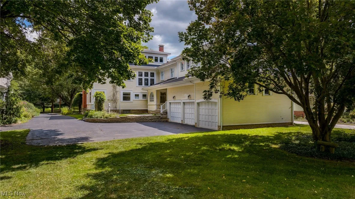 View of front of house with a garage, asphalt driveway, and a front lawn