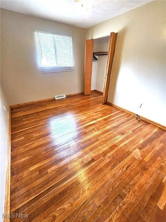 Unfurnished bedroom featuring a closet, light wood-style floors, and a textured ceiling