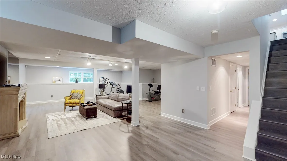 Living area with stairway, recessed lighting, light wood-style floors, and a textured ceiling