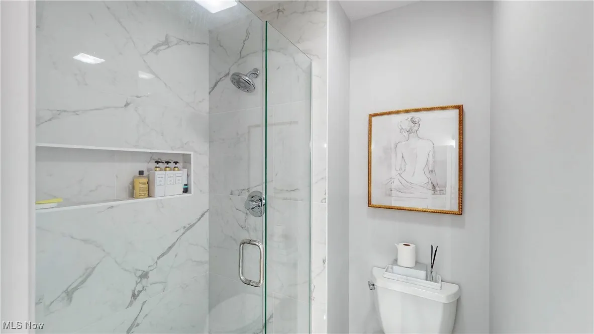Bathroom featuring a marble finish shower and toilet