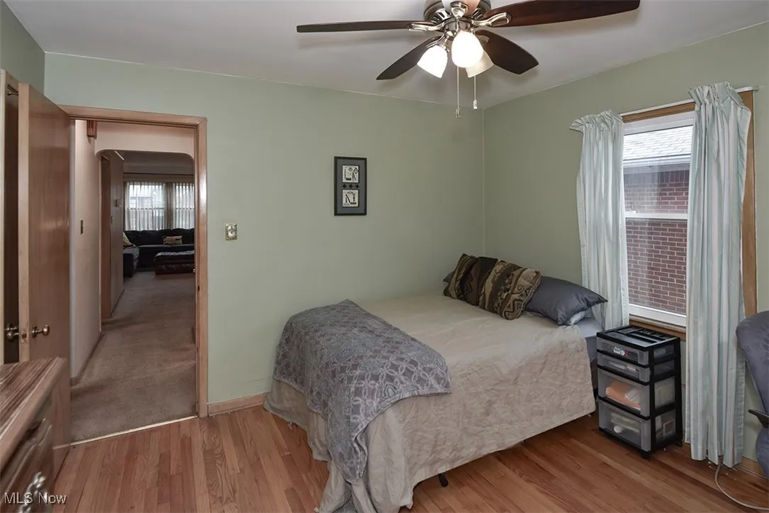 Bedroom with multiple windows, wood finished floors, a ceiling fan, and arched walkways