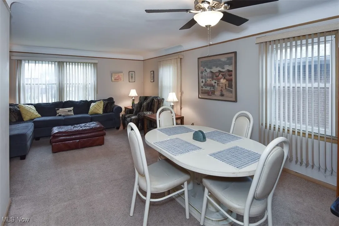 Dining room with light colored carpet and a ceiling fan