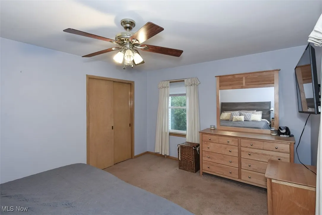 Bedroom with light carpet, a closet, and ceiling fan