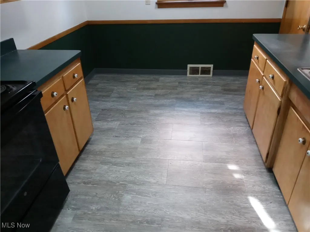 Kitchen with dark countertops, black range, and brown cabinetry
