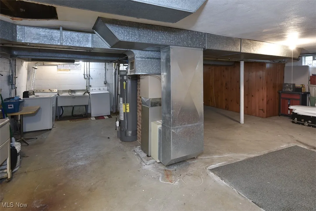 Below grade area featuring heating unit, water heater, and independent washer and dryer